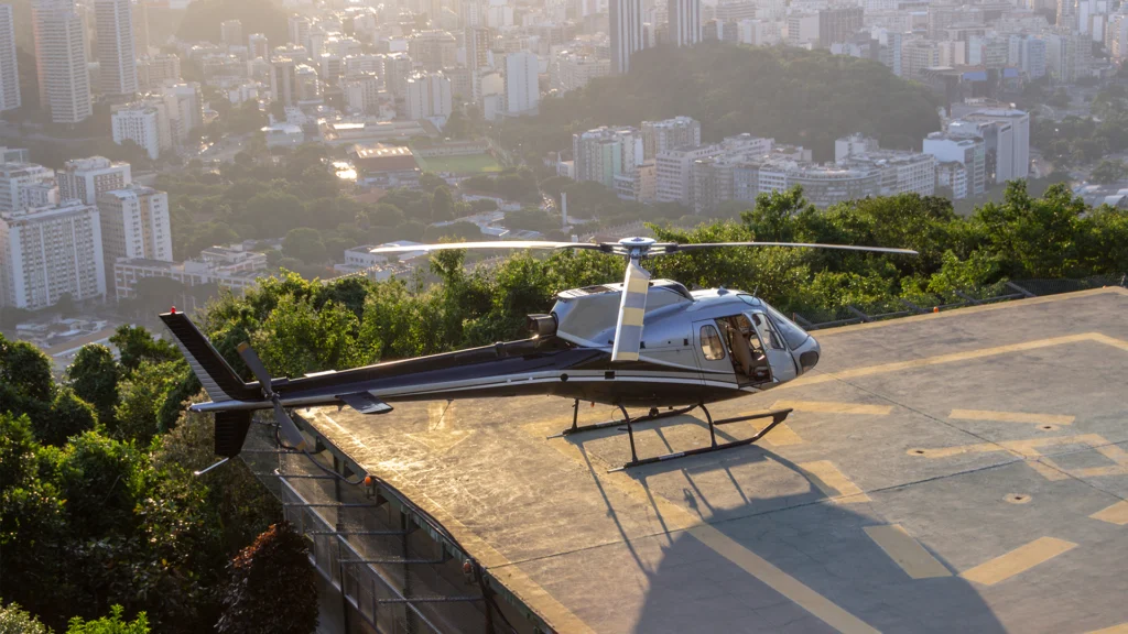 Helicóptero pousando em heliponto hospitalar com equipe de emergência aguardando o desembarque do paciente, transmitindo agilidade e infraestrutura de ponta na área da saúde.